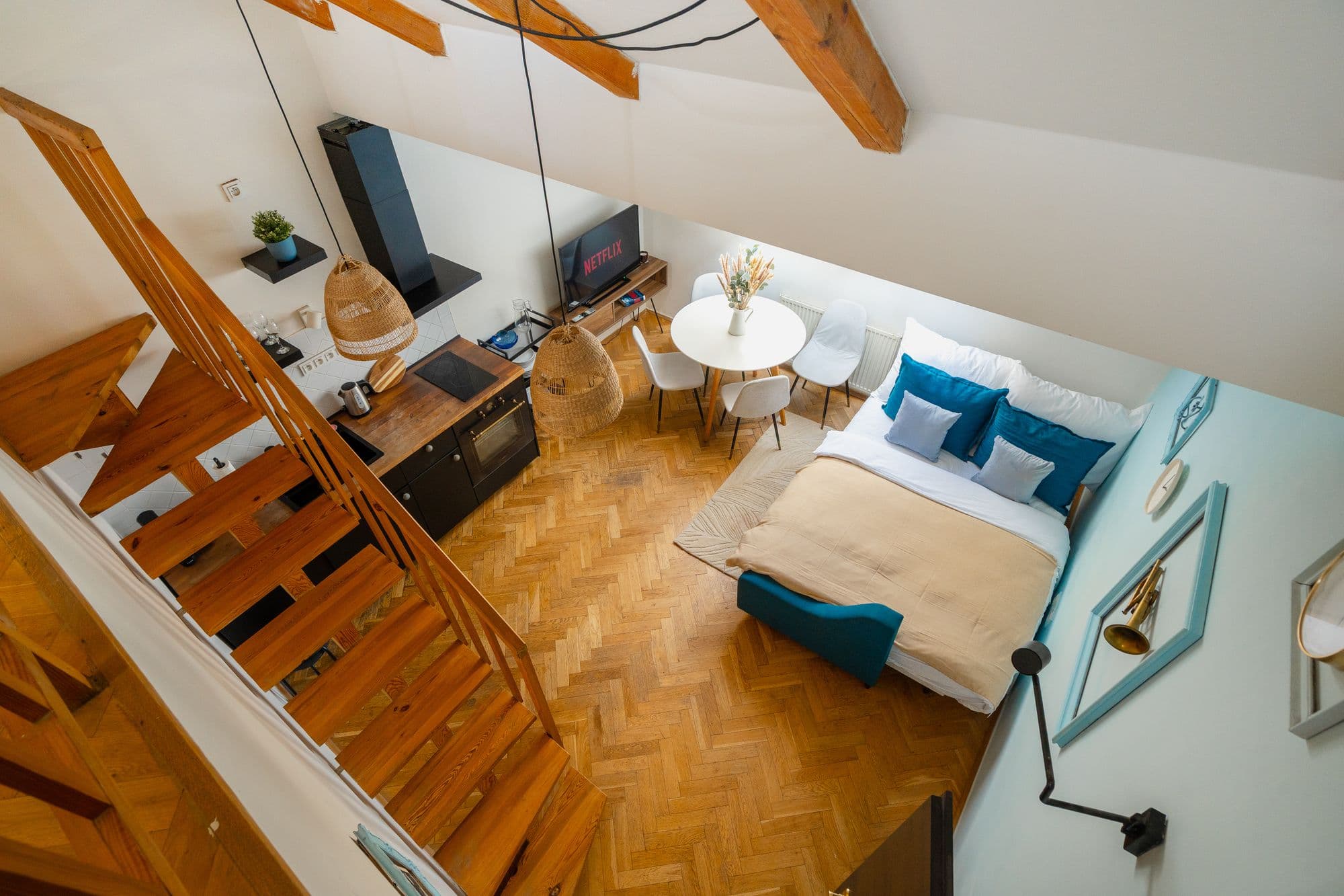 View from the gallery down onto the open-plan living space, with the staircase, kitchenette, dining table and sofa bed