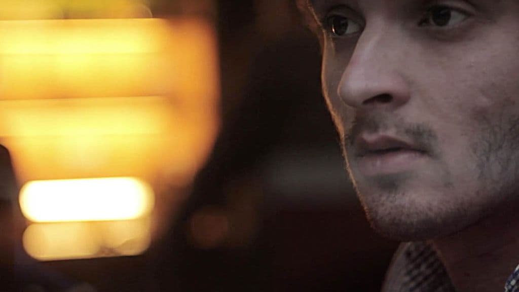 Still from the Estée Lauder spot A Moment of Seduction: close-up of a man's face in low light beside a blurred warm glow.