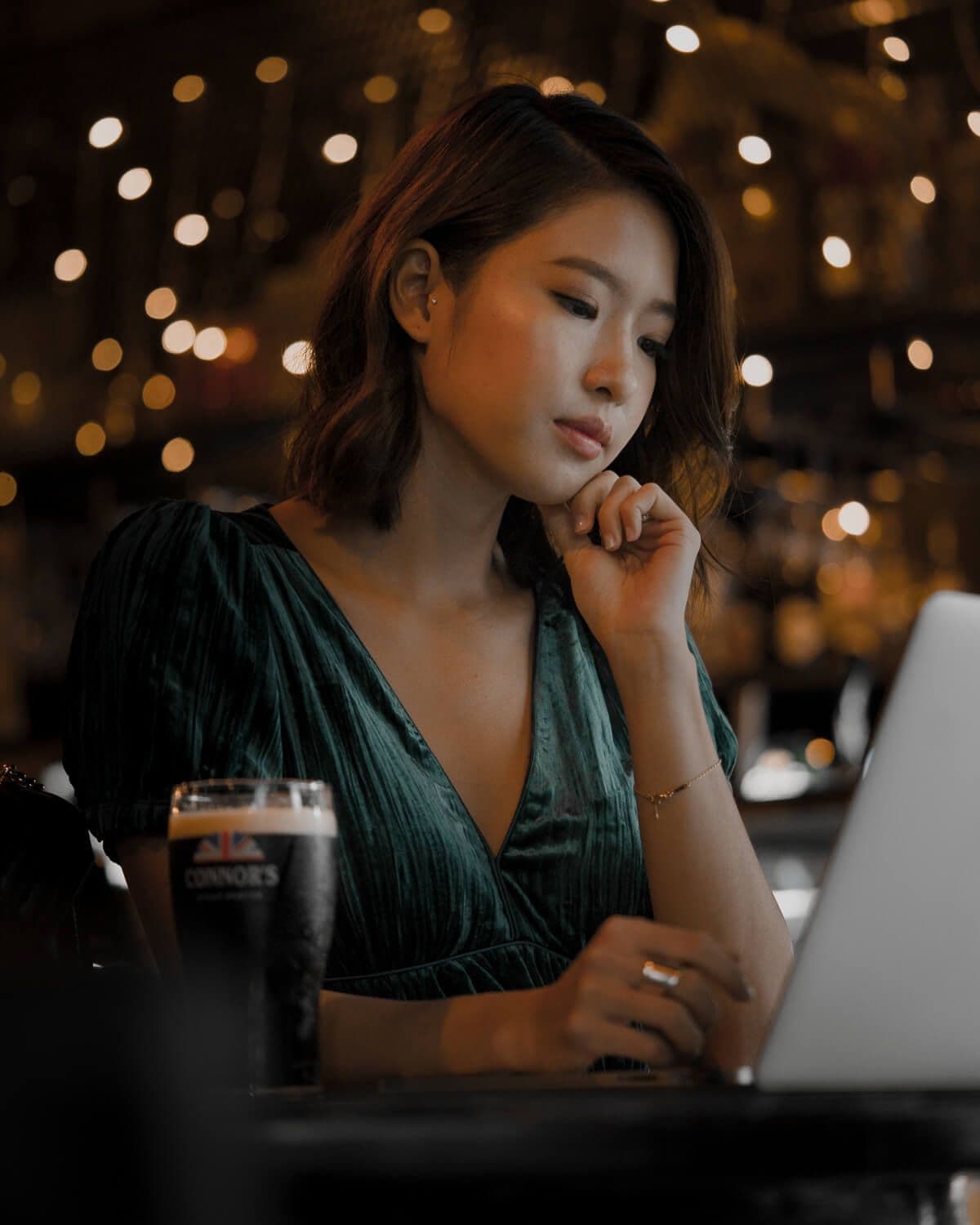 Bella Kuan looking at a laptop in a bar, a pint of Connor’s stout beside her.